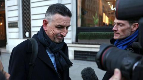 Fujitsu Europe chief Paul Patterson wears a coat and scarf as he leaves the Post Office Horizon IT Inquiry in central London.