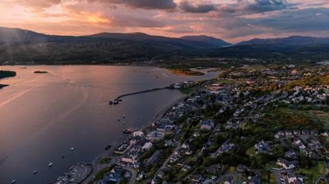 An aerial view of Fort William, showing houses and businesses, Loch Linnhe and hills on the opposite shore