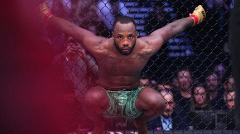 Leon Edwards crouches in the octagon and hangs onto the cage before a fight