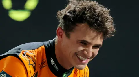 McLaren's Lando Norris leans over and smiles after taking pole position for the Las Vegas Grand Prix