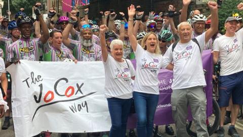 Jo's parents Jean and Gordon Leadbeater and her sister Kim with riders at The Jo Cox Way 2025 finish line