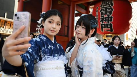Two Chinese tourists wear kimonos as they visit the Sensoji Temple in the Asakusa district of Tokyo on November 15, 2025.
