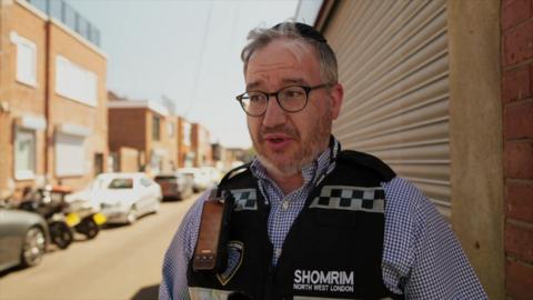 Isaac looks directly at the camera while wearing a Shomrim uniform