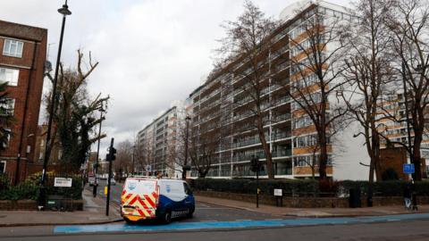 Street view of a residential estate in Pimlico, central London, with several mid-rise apartment blocks lining a tree-lined road. A Thames Water van is parked at a junction in the foreground beneath an overcast sky.