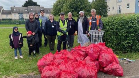 People stood with full rubbish bags