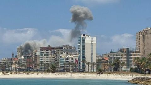 smoke rises over tyre in this shot taken from a beach.