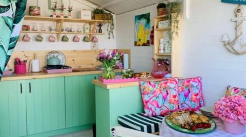 The interior of a beach hut with Palm Springs colours and a table set for lunch