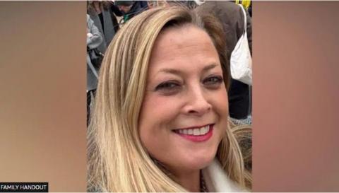 Annabel Rook is looking at the camera smiling. She has long blonde hair and is wearing make up. There are people in the background behind her and the photo was taken outside.