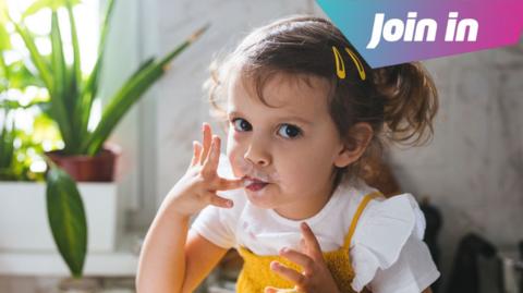 Girl licking her fingers with food on them.
