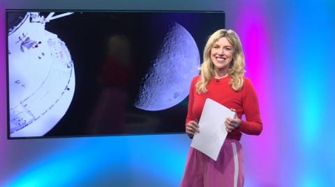 Jenny in the studio with a moon in the screen