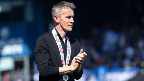 Kieran McKenna clapping after winning promotion with a medal around his neck