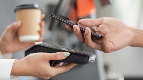 Someone making a contactless payment on their phone