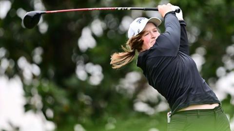 Lottie Woad swings a golf club 