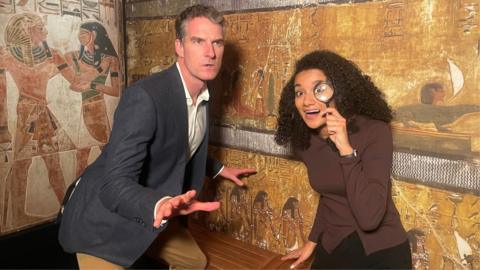 Historian Dan Snow and presenter Nina Blissett strike poses in front of a mock up of an Ancient Egyptian wall engraving.