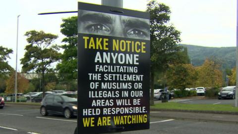 A poster that reads 'Take notice anyone facilitating the settlement of Muslims or illegals in our areas will be held responsible. We are watching' it also has a picture of a persons eyes along the top of the poster.