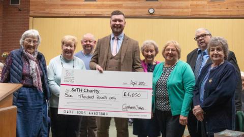 Members of Cickers standing around a cheque made out to the hospital trust, donating £6,000