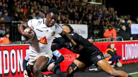 Exeter winger Paul Brown-Bampoe (left) with the ball in his right hand goes through an attempted tackle from Elliot Obatoyinbo