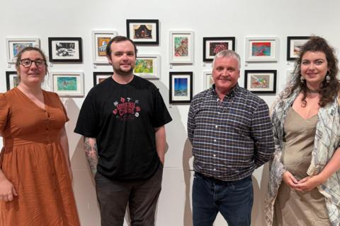 From left to right, a women looking at the camera and smiling. She is wearing glasses and has brown hair which is scraped back. She is wearing a rusty brown colour dress. A man looking at the camera and smiling.He has short dark hair and a short beard. He is wearing a black t shirt with red writing on. He has his hands in his pockets. A man looking at the camera and smiling. He has his hands behind his back. He has grey hair and is wearing a long sleeved patterned shirt and blue jeans. A women looking at the camera and smiling. She has her hands clasped together by her stomach. She is wearing a silk style long dress and a shoal that has a vintage map of Paris print. She has medium length brown hair.