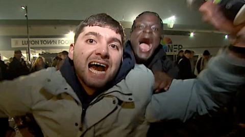 Two happy football fans shouting and cheering at camera.