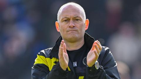 Alex Neil faces the camera while clapping