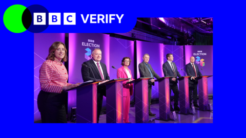 Six people - four men and two women standing behind podiums during a TV debate for the 2026 Welsh Senedd election. There is purple BBC election branding behind them.