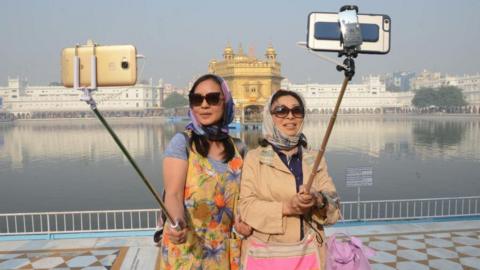 Chinese tourists take a 'selfie' at the Golden Temple in Amritsar on November 14, 2016, as Sikh devotees mark the 547th birth anniversary of Sri Guru Nanak Dev. Guru Nanak was the founder of the Sikh religion and the first of ten Sikh gurus.
