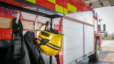 A fireman's helmet hangs by a fire engine in a fire station.