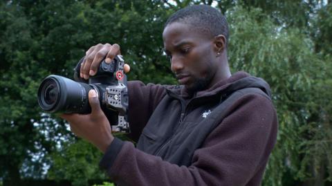 Baka Bah filming with a camera outside