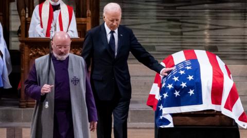 Biden touching Carter's casket