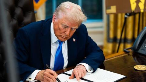 Donald Trump sits at the Oval Office Resolute Desk and is signing an executive order on a visa for skilled workers 