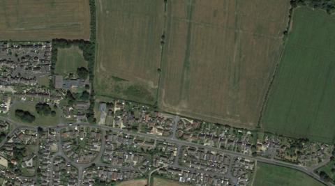 An aerial image of Fiskerton village with several houses and agricultural land in the top right for the new homes