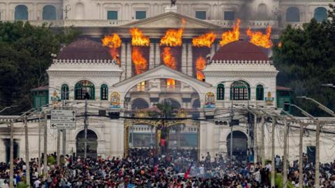 Parliament building in Nepal on fire, crowds stood outside.
