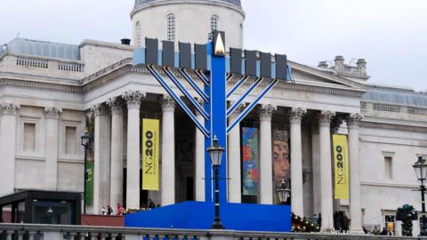 Trafalgar Square Menorah in front of the National Gallery, with one candle lit, marking the celebration of Chanukah.