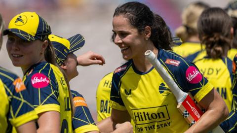 Maia Bouchier wearing a yellow Hampshire top smiles