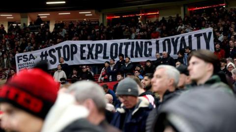 Fans hold a banner reading 'Stop Exploiting Loyalty' in a protest against ticket price increases before Manchester United's match against Fulham in the FA Cup at Old Trafford