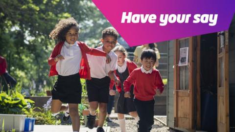 Chidlren in school uniform running outside next to a flower bed and a shed