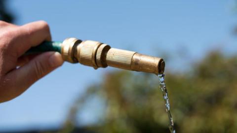 A person holding a hosepipe.