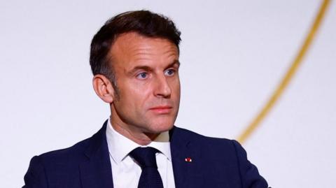 A head and shoulders image of Emmanuel Macron in a blue suit and dark tie