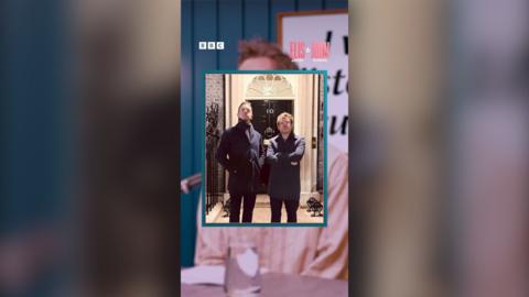 A photo of Elis and John dressed in elegant black suits at the entrance of 10 Downing Street, the official residence of the UK Prime Minister.