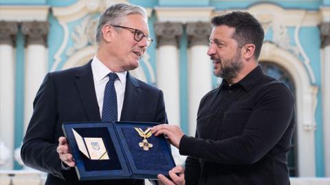 Starmer holds a medal Zelensky gives him as they speak to each other