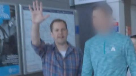 A screengrab of Robert Jenrick holding up his hand as he confronts a fare dodger, whose face is blobbed out, at a Tube station.