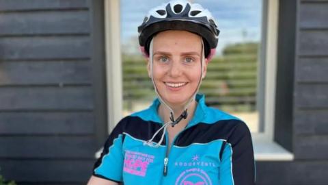Woman smiling wearing a cycling helmet and t-shirt