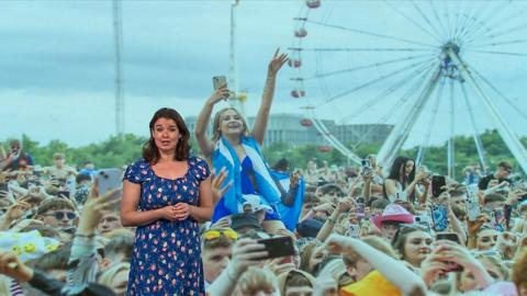 Gillian Smart stands in front of an image of TRNSMT music festival