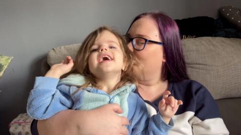 Angel-Kay Mason and three-year-old daughter Aria cuddling on the floor in their lounge in front of a sofa