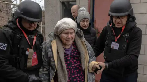 Volunteers of East SOS Charity Foundation help an elderly woman to walk as she is evacuated from her house, as the result of constant air attacks, in Kostyantynivka, in the eastern Donetsk region, on March 17, 2025, amid the Russian invasion of Ukraine. 