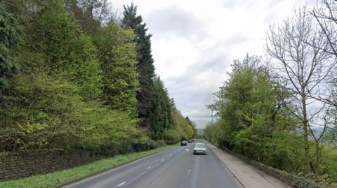 The A660 looking towards Otley with trees and greenery on either side of the ride