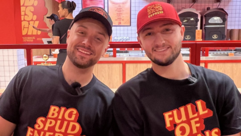 Jacob and Harley Nelson wearing black, red and yellow branded T-shirts and caps
