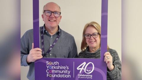 Chief executive Martin Singer and head of philanthropy and programmes Michelle Dickinson from South Yorkshire's Community Foundation. They are holding a purple frame with the foundation's logo.