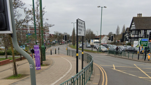 A google street view of a main road with cars on the far right hand side of the road. 