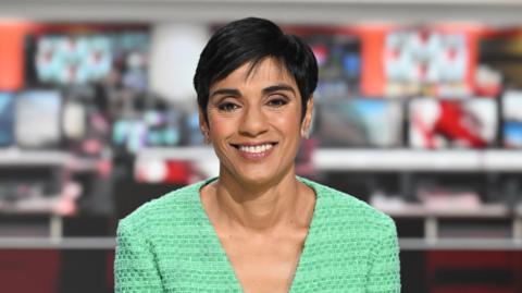 Reeta Chakrabarti presenting the BBC News at 6 on BBC One,  wearing a green v-neck top